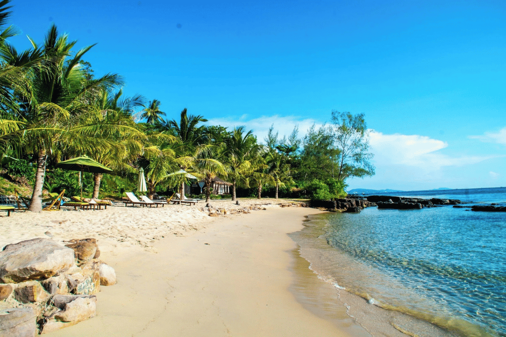 Quiet palm-fringed Ong Lang Beach with rocks and calm, clear water