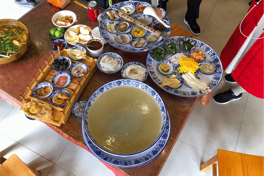 Table spread of Yunnan dishes including a clear broth, rice and small side plates