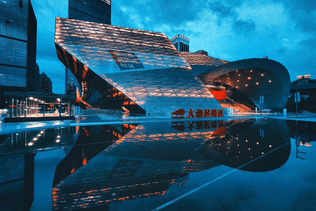 Angular modern museum building lit up and reflected in the plaza pool at dusk