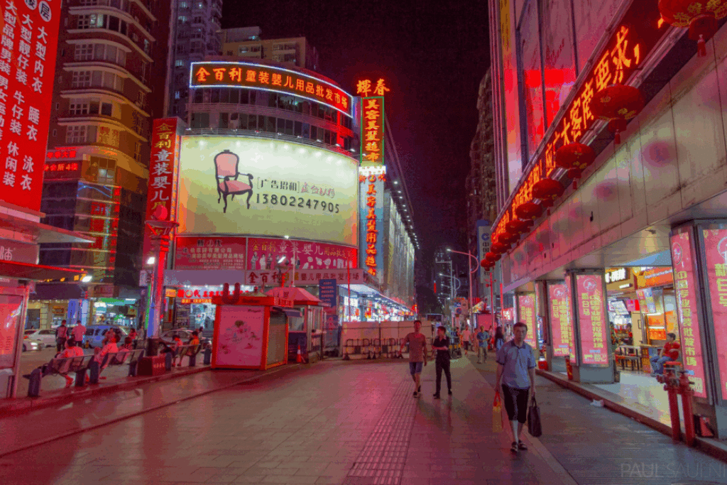 Neon billboards and shopfronts lighting up a busy Shenzhen street at night