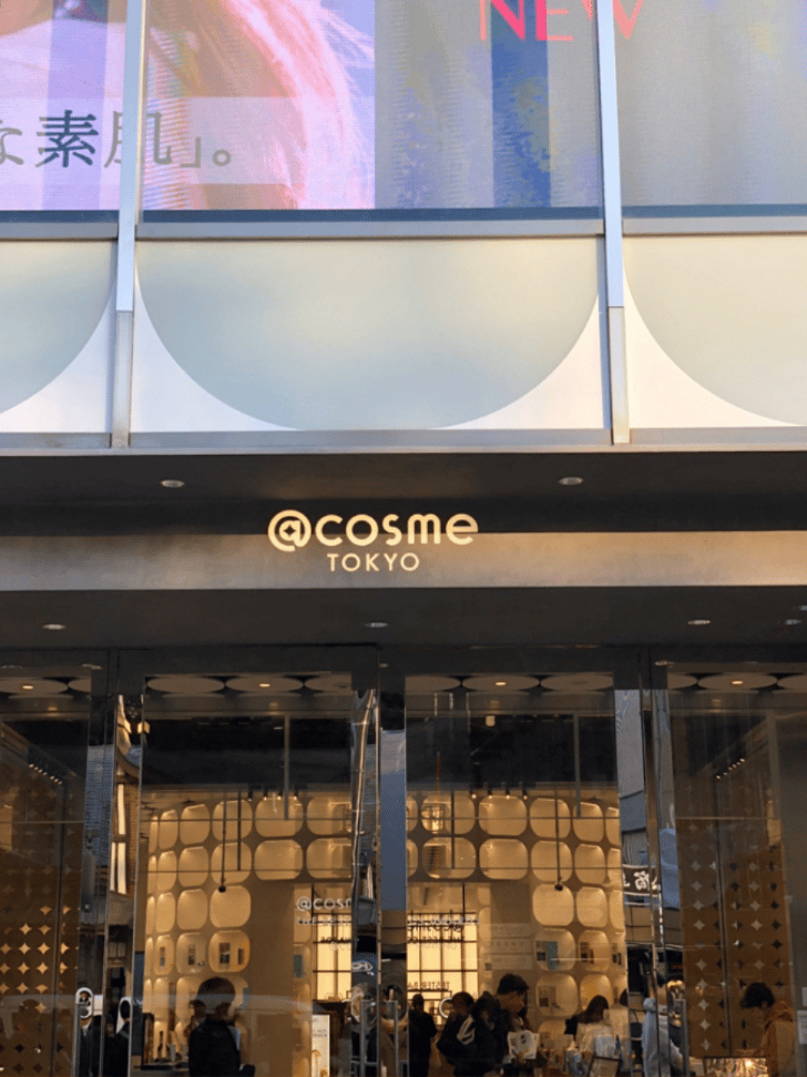 The @cosme TOKYO storefront entrance with its logo above the glass doors in Harajuku