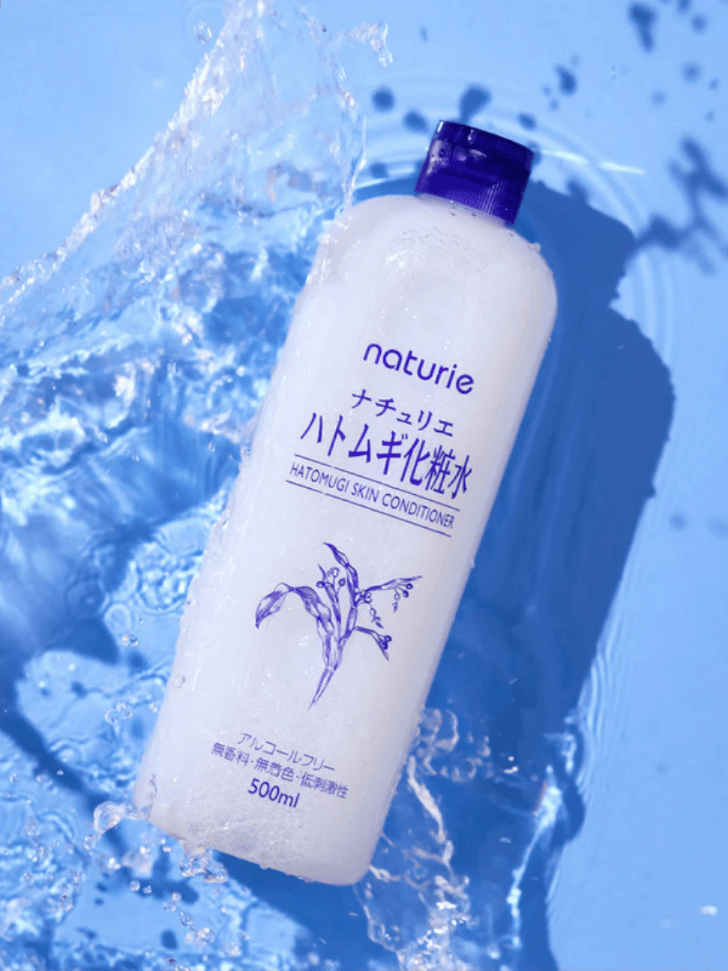 Naturie Hatomugi Skin Conditioner lotion bottle against a splash of water