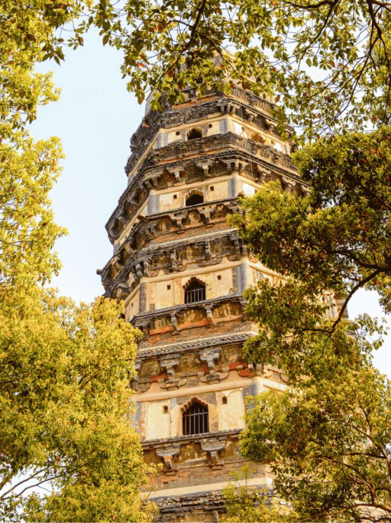 The tilting brick Tiger Hill Pagoda framed by trees against the sky