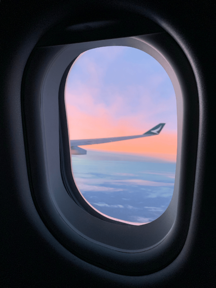 View of an aeroplane wing through the cabin window at sunset