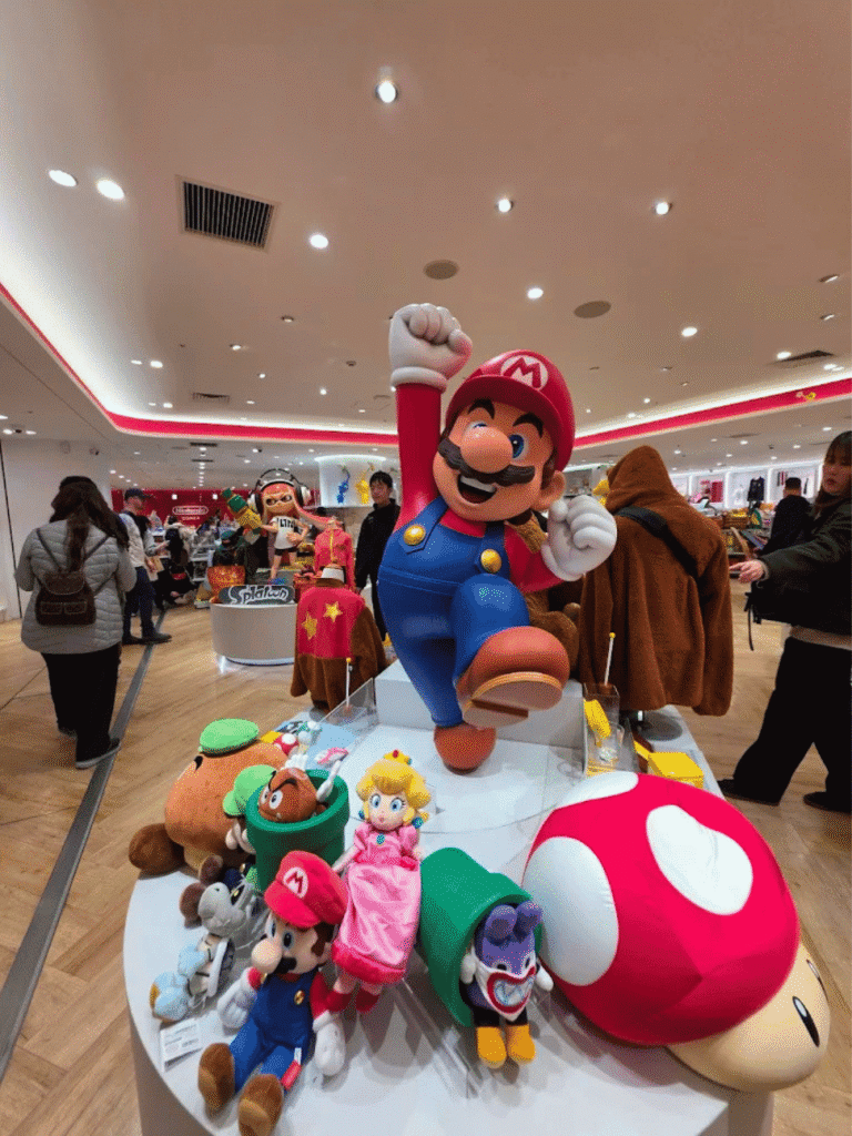 Large Super Mario statue surrounded by Peach, Yoshi and mushroom plush at the Nintendo Osaka store