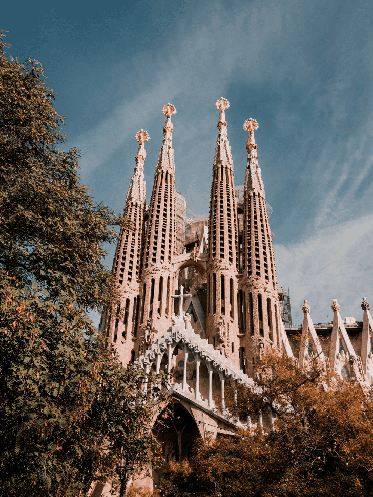 Sagrada Familia basilica spires in Barcelona framed by trees against a blue sky