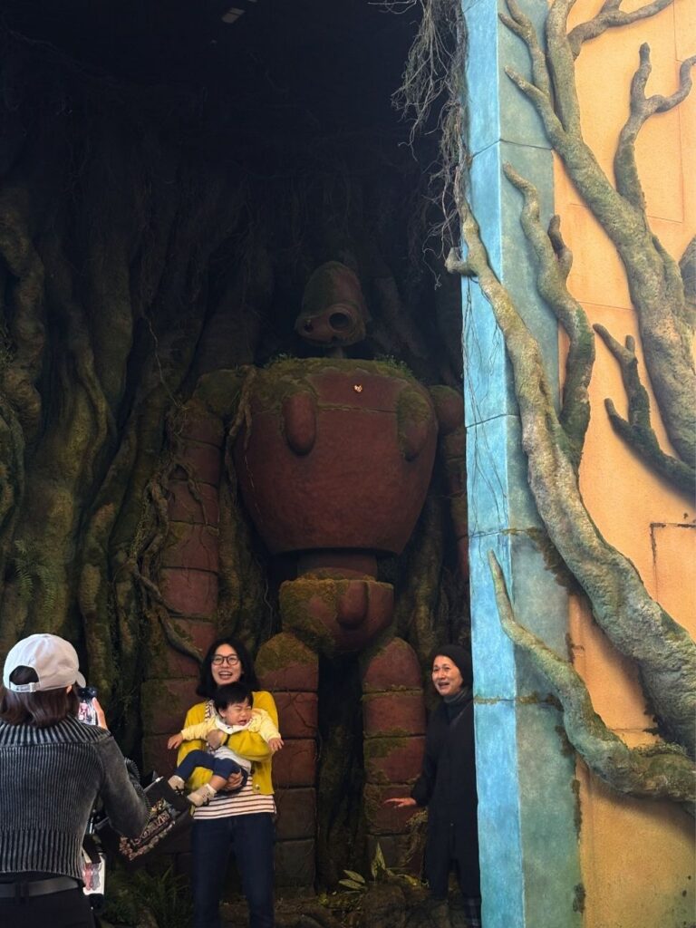 Visitors posing with the mossy Robot Soldier from Castle in the Sky at Ghibli's Grand Warehouse