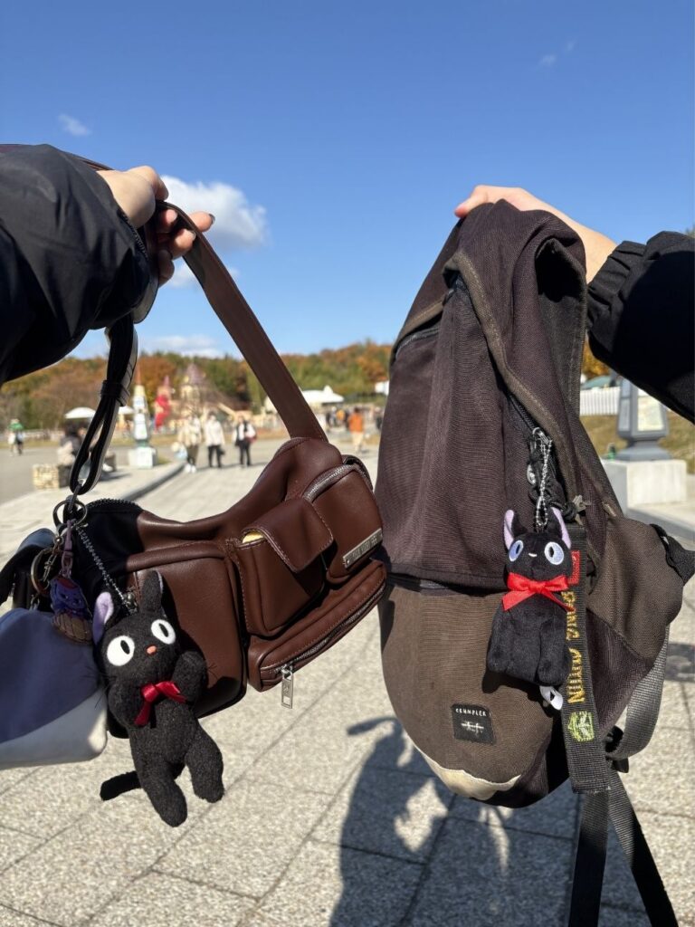 Two Jiji black-cat plush keychains from Kiki's Delivery Service clipped to bags at Ghibli Park