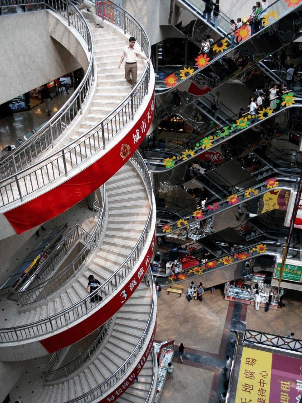 Spiral staircase and escalators inside a busy multi-storey Shenzhen shopping mall
