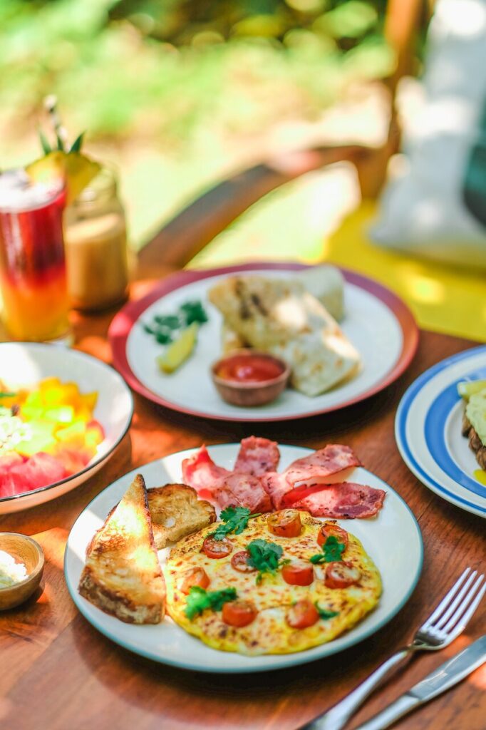 Outdoor brunch of omelette, bacon, toast and tropical drinks at a Bali café