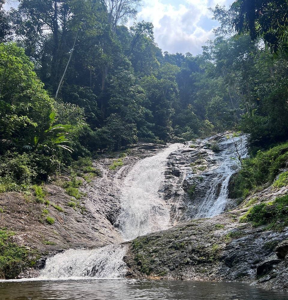 Water cascading down rocks surrounded by jungle at Lata Iskandar Waterfall