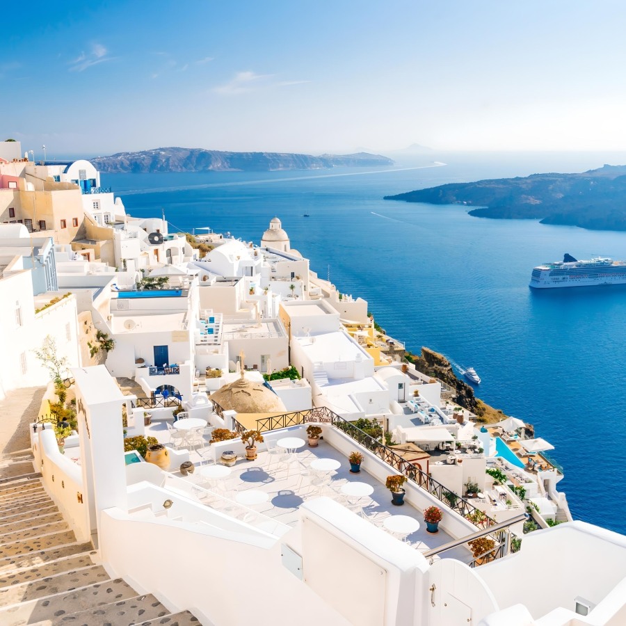 Fira's white buildings cascading down the caldera cliff with a cruise ship on the blue water