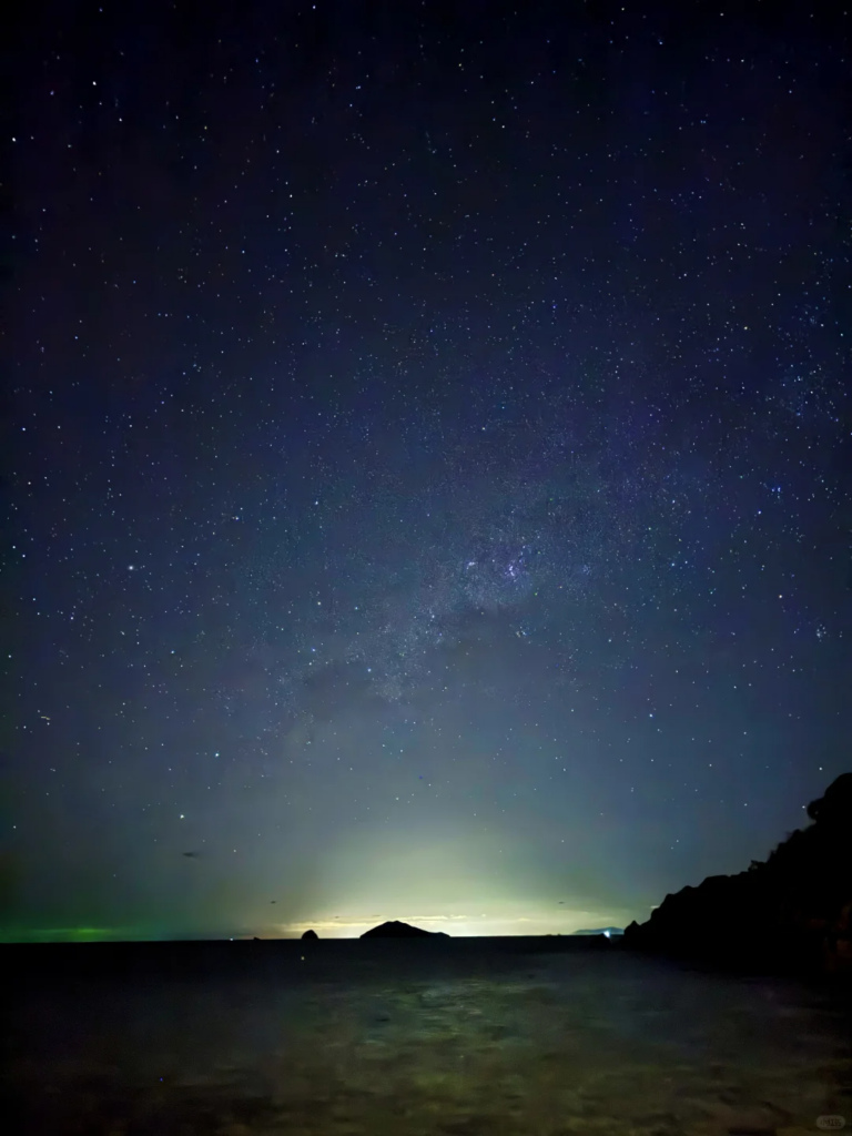 Starry night sky and the Milky Way over the sea with an island silhouette