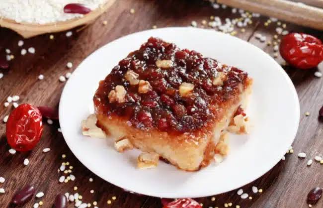 A slice of zenggao, steamed glutinous rice cake topped with dates and nuts