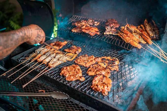 Prawn and chicken skewers grilling over a smoky barbecue