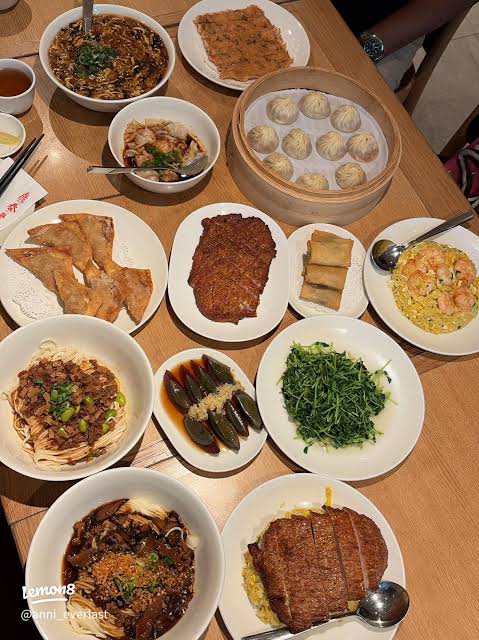 Table spread of Din Tai Fung dishes including xiao long bao and noodles