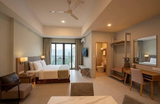 Modern hotel room with a bed, desk and balcony at Zenith Suites, Tanah Rata