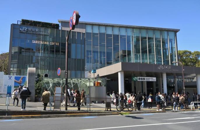 JR Harajuku Station building with travellers gathered outside on a sunny day