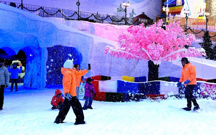 Visitors in jackets playing in artificial snow at Genting's indoor Snow World