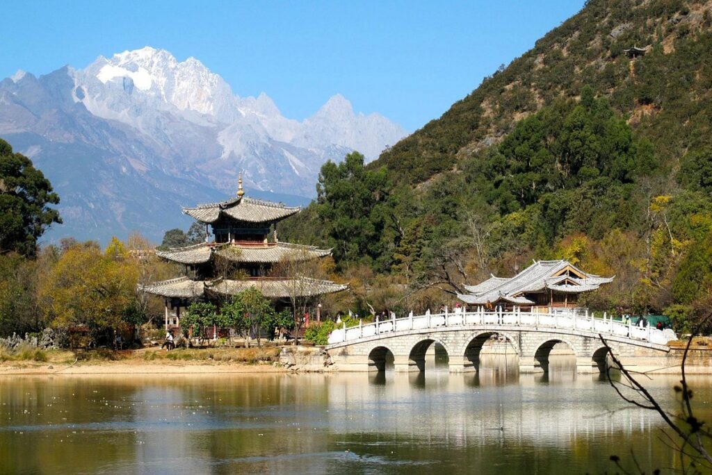 Pavilion and white arched bridge reflected in Black Dragon Pool below Jade Dragon Snow Mountain