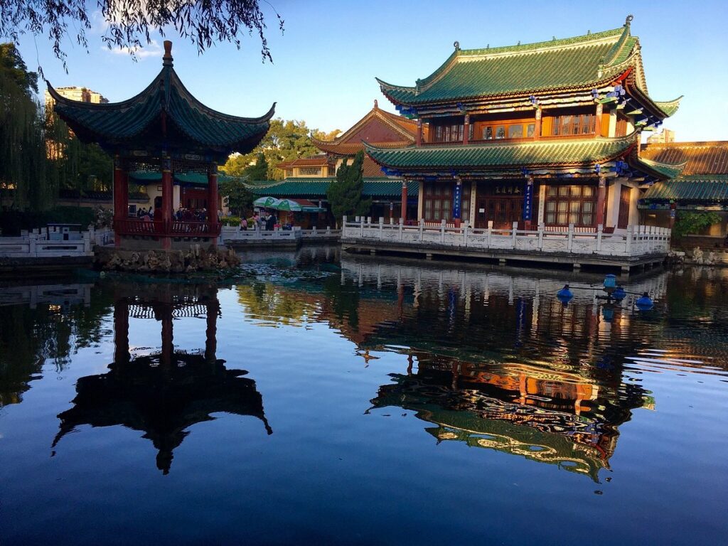 Traditional pavilion and hall reflected in the calm water of Green Lake Park, Kunming