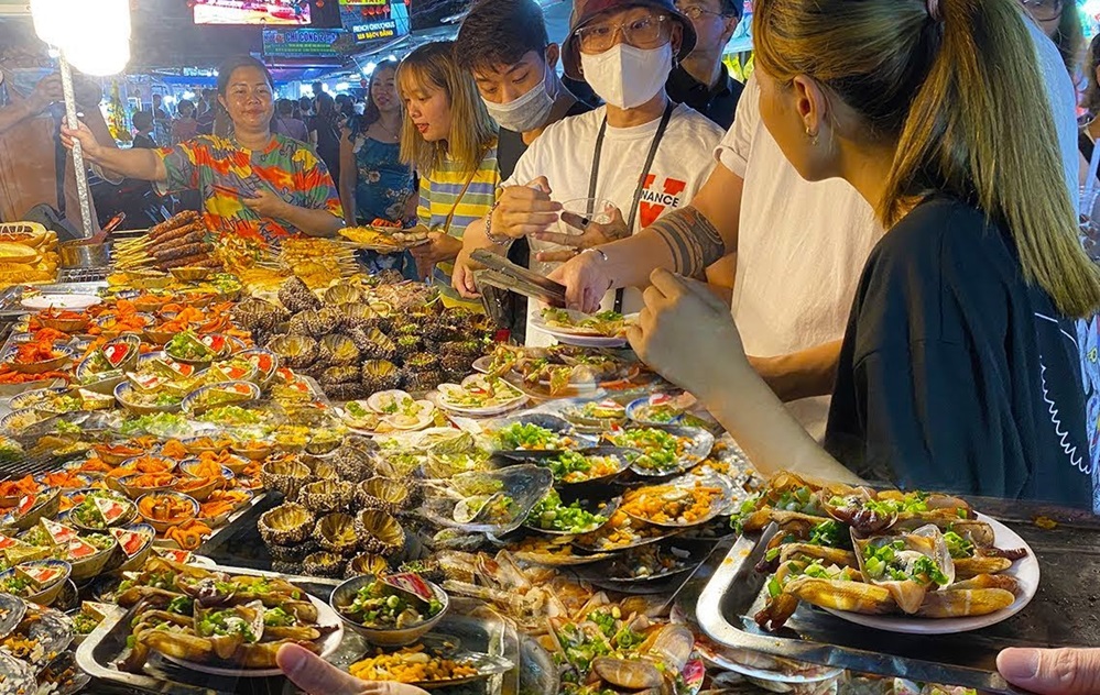 Tourists browsing stalls piled with fresh seafood at Duong Dong Night Market