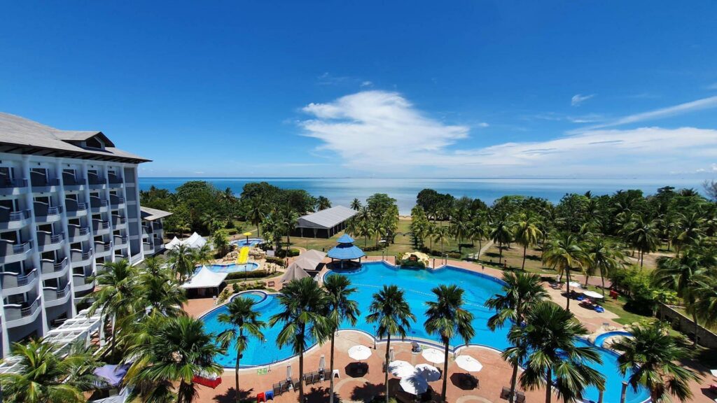 Large beachfront resort with a big pool, palm trees and sea views