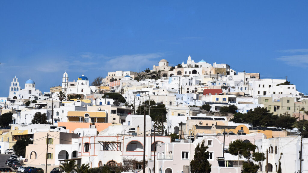 The hillside village of Pyrgos climbing to a castle, with blue-domed churches and bell towers