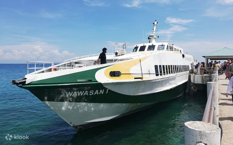 A catamaran passenger ferry docked at a jetty under blue skies, bound for Tioman