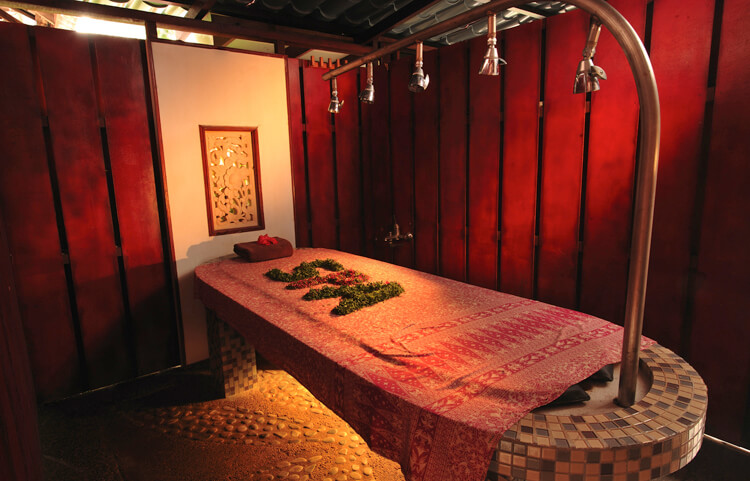 A traditional spa treatment room with a massage table and rainfall showers