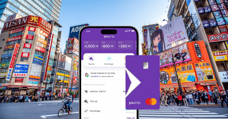 The YouTrip app open on a phone in front of a neon-lit Tokyo street