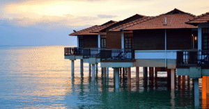 Over-water villas on stilts above a calm sea at dusk in Port Dickson