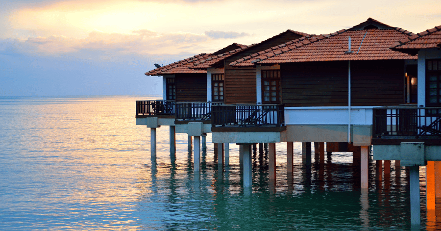 Over-water villas on stilts above a calm sea at dusk in Port Dickson