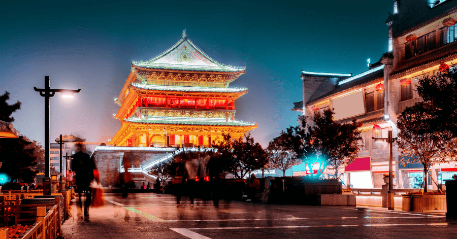 Xi'an's Drum Tower illuminated gold at night above a busy city street