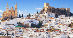 Whitewashed Andalusian hilltop town with a church and Moorish castle above red rooftops
