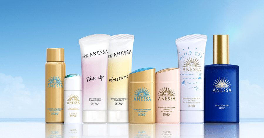 The Anessa sunscreen range lined up on a reflective surface against a blue sky