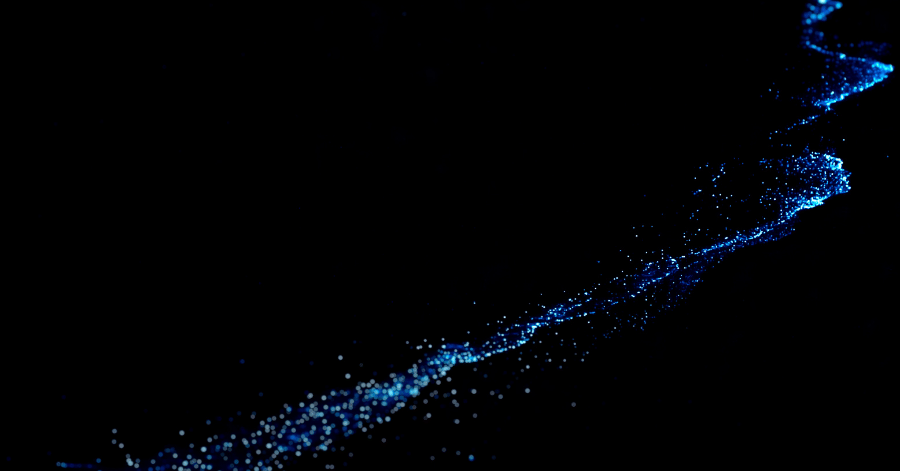 Blue bioluminescent plankton glowing in dark seawater at night