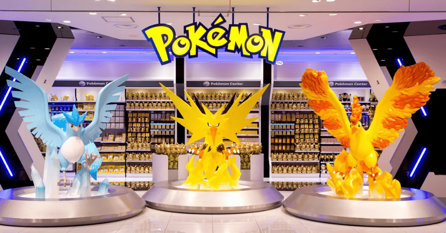 Three large illuminated legendary Pokémon statues on individual pedestals beneath a glowing Pokémon sign