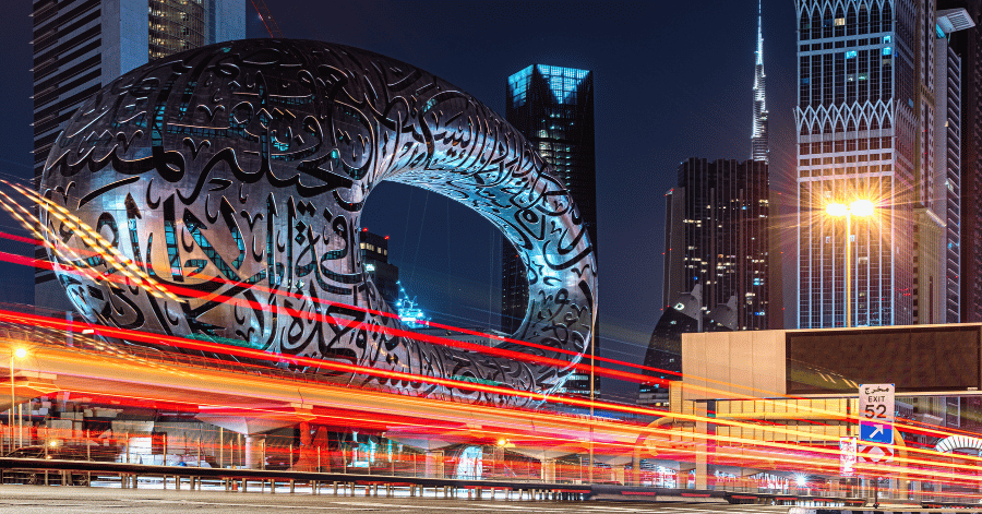 Dubai's Museum of the Future at night, a ring-shaped building with Arabic calligraphy and traffic light trails
