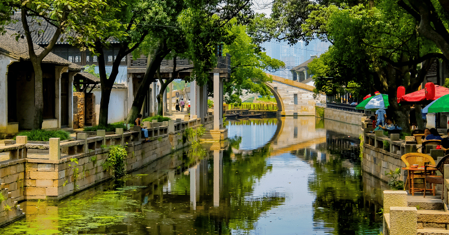 A quiet Suzhou canal lined with traditional white houses and willow trees