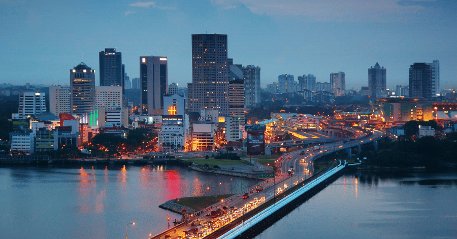 Johor Bahru's waterfront skyline at dusk, with a lit causeway crossing the water