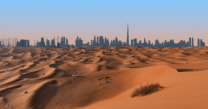 Dubai skyline with the Burj Khalifa rising beyond red desert dunes at dusk