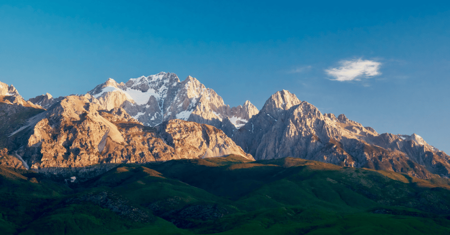 Snow-capped mountain range rising above green highland slopes at sunrise in Yunnan