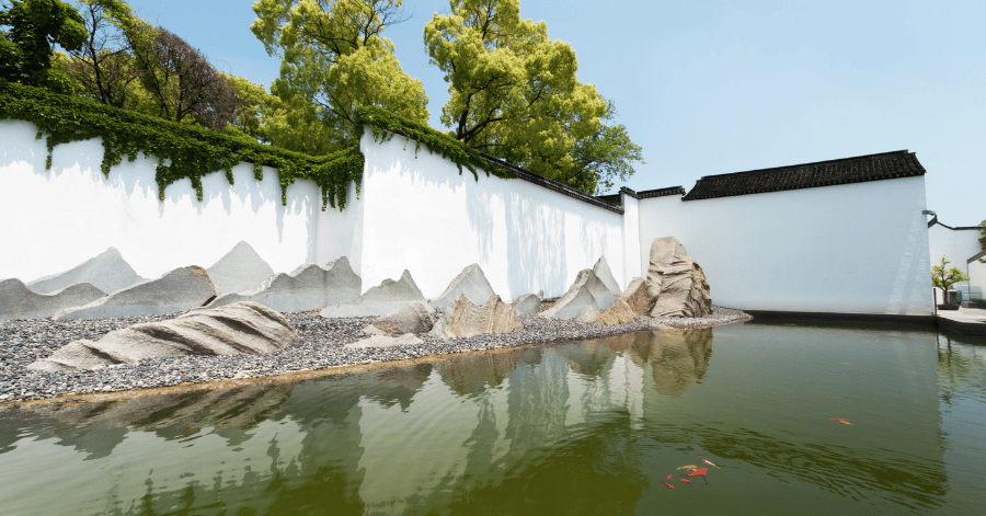 The Suzhou Museum's white wall and stone rockery reflected in a courtyard pond