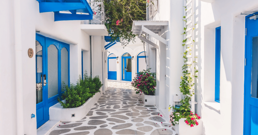 A quiet whitewashed village lane with blue doors and pink bougainvillea, Santorini