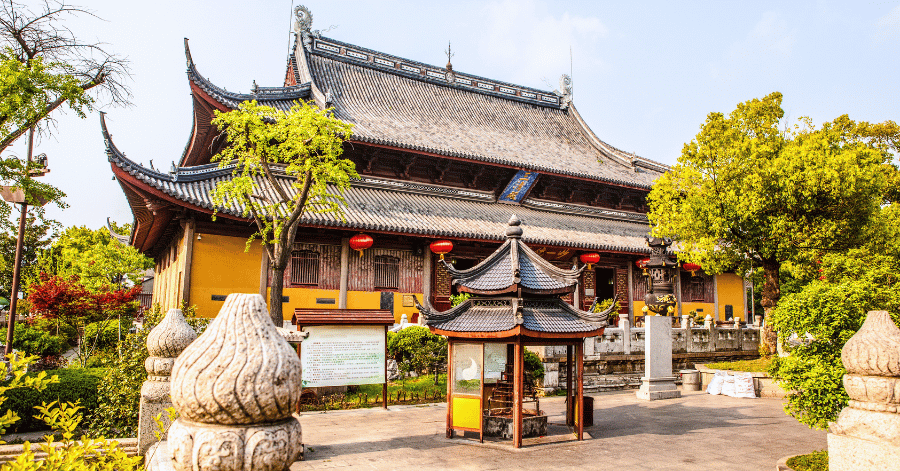 The main hall of the Taoist Xuanmiao Temple with red lanterns and a stone lion