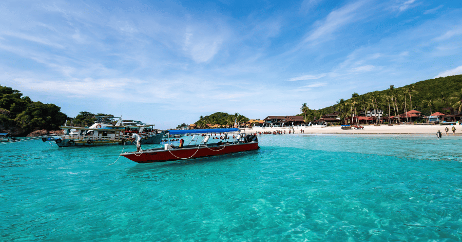 Wooden passenger boat in shallow turquoise water off a Redang Island beach
