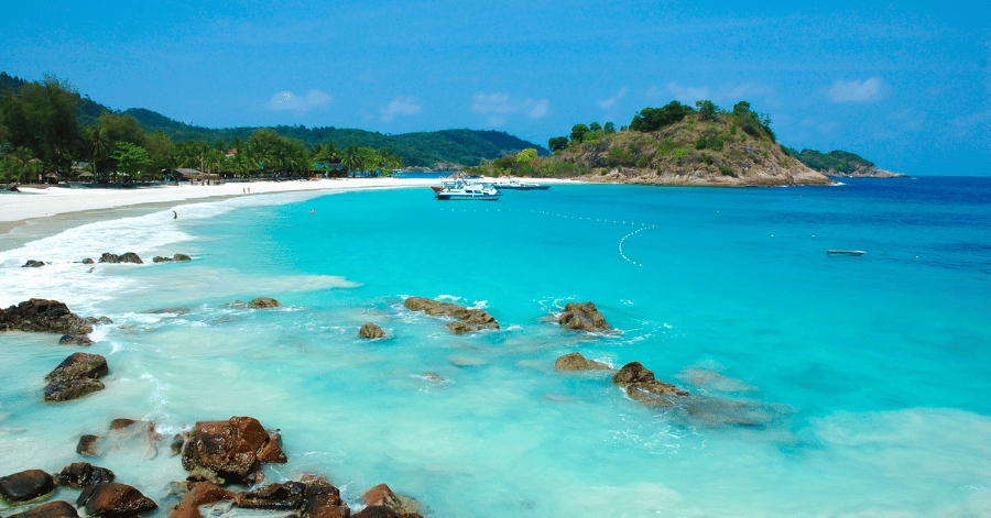 White-sand beach and clear turquoise water at Redang Island, with a rocky islet offshore