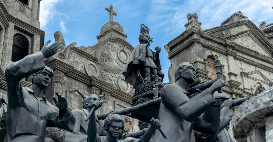 Bronze sculptural monument of historical figures in front of a Spanish baroque church, Cebu