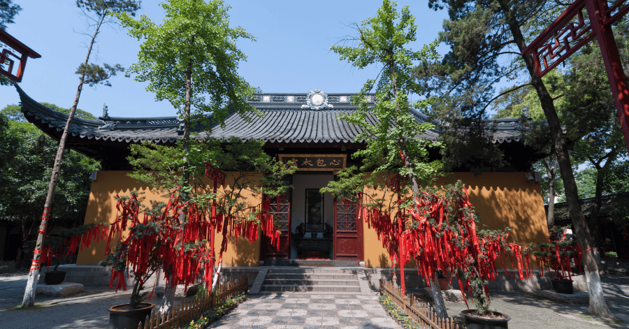 Yellow temple walls hung with red prayer ribbons in Hanshan Temple's courtyard